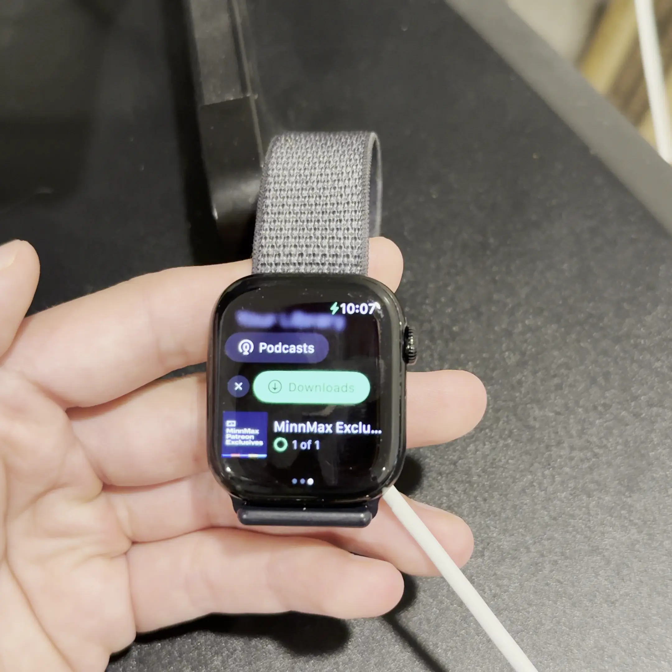 A hand holding an Apple Watch. The Spotify app is open and an indeterminate spinner is spinning